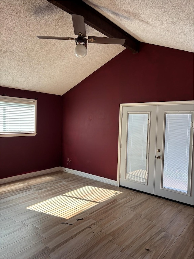 interior space with vaulted ceiling with beams, ceiling fan, french doors, and a healthy amount of sunlight