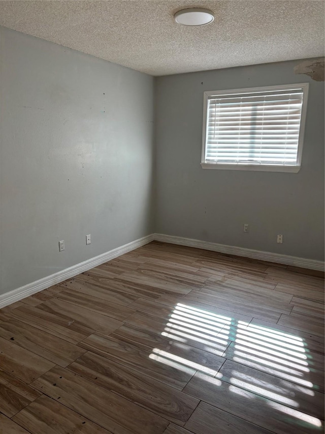 empty room featuring hardwood / wood-style flooring and a textured ceiling