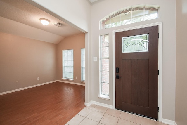 foyer entrance with light tile patterned floors, a textured ceiling, and lofted ceiling