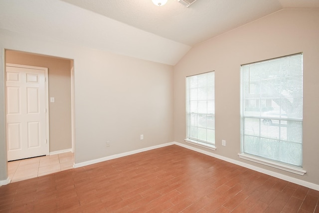 unfurnished room featuring light wood-type flooring and lofted ceiling