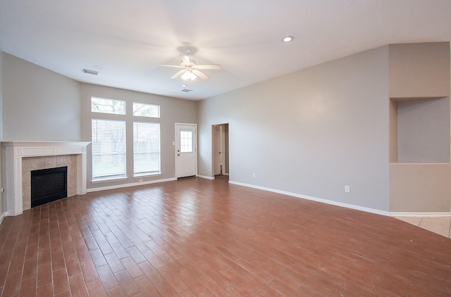 unfurnished living room featuring hardwood / wood-style flooring, ceiling fan, and a fireplace