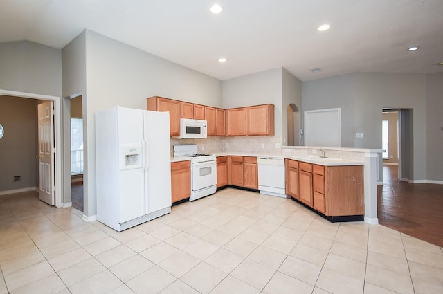 kitchen with white appliances, backsplash, sink, light tile patterned floors, and kitchen peninsula