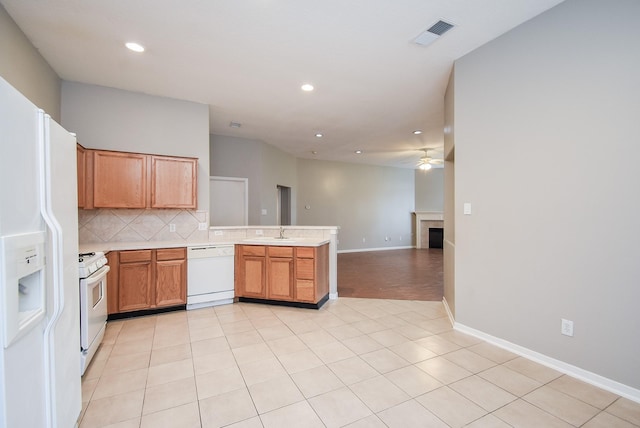 kitchen with kitchen peninsula, backsplash, white appliances, sink, and light tile patterned floors