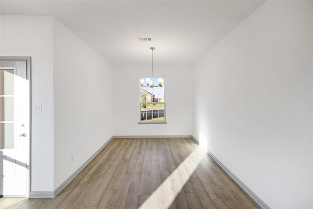 unfurnished dining area featuring a notable chandelier and light hardwood / wood-style flooring