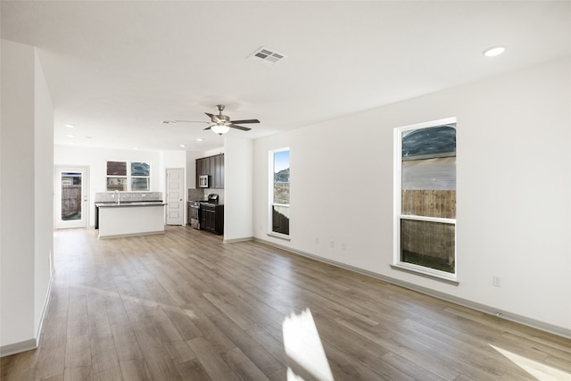 unfurnished living room featuring sink, ceiling fan, and light hardwood / wood-style flooring