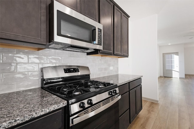 kitchen with stainless steel appliances, stone countertops, light hardwood / wood-style floors, and dark brown cabinetry