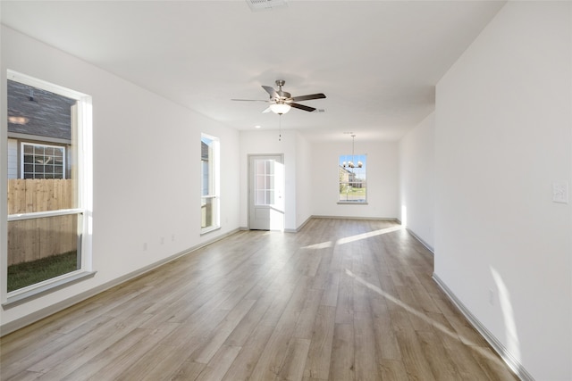 unfurnished room featuring ceiling fan with notable chandelier and light hardwood / wood-style flooring