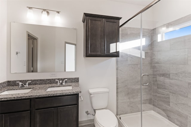 bathroom featuring toilet, a shower with door, and vanity