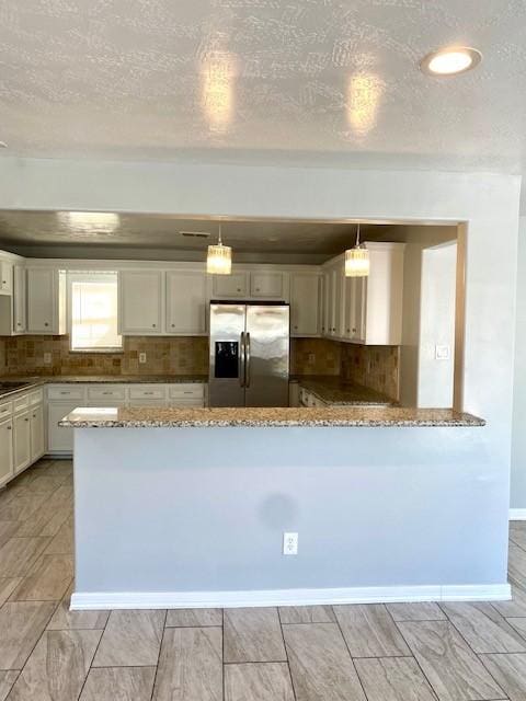 kitchen featuring kitchen peninsula, stainless steel refrigerator with ice dispenser, and decorative light fixtures