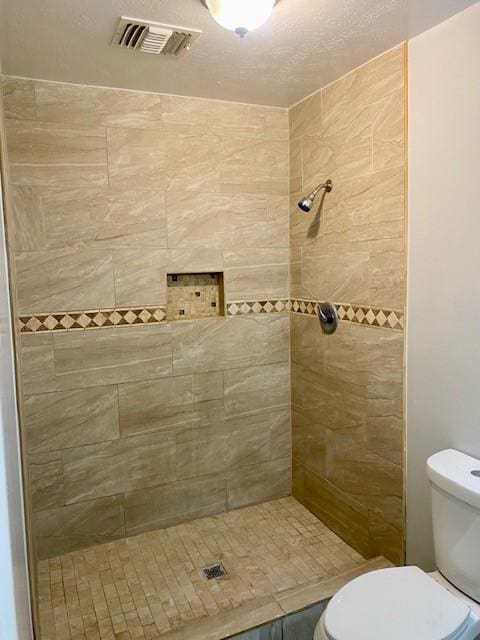 bathroom featuring tiled shower and toilet