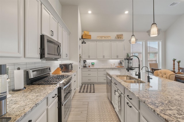 kitchen featuring white cabinets, appliances with stainless steel finishes, decorative light fixtures, and sink