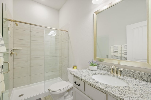 bathroom featuring a shower with door, vanity, and toilet