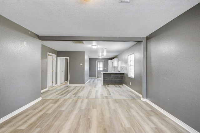 unfurnished living room featuring a textured ceiling and light hardwood / wood-style flooring