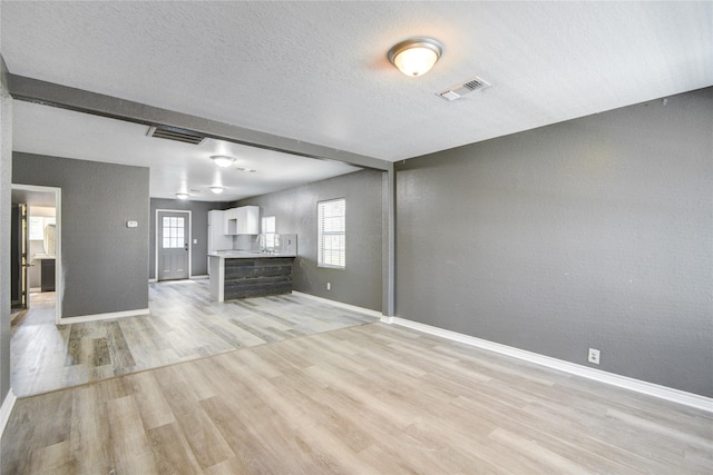 unfurnished living room with a textured ceiling and light wood-type flooring