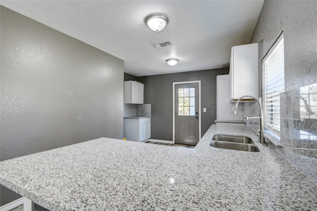 kitchen with white cabinets, kitchen peninsula, and sink