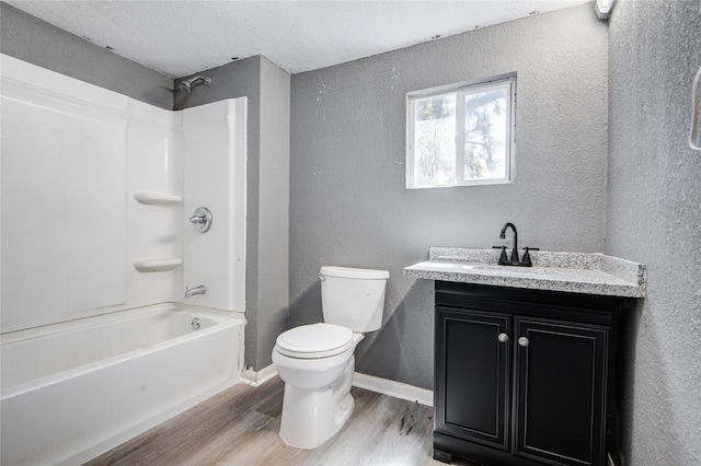 full bathroom with vanity, a textured ceiling,  shower combination, wood-type flooring, and toilet