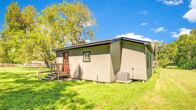 back of property featuring a lawn and central air condition unit