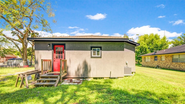 back of property with a yard and central AC