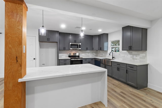 kitchen with backsplash, sink, light stone countertops, decorative light fixtures, and stainless steel appliances