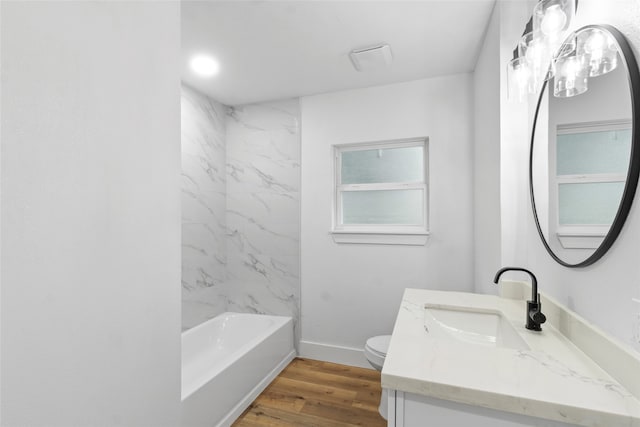 full bathroom with vanity, wood-type flooring, tiled shower / bath combo, and toilet