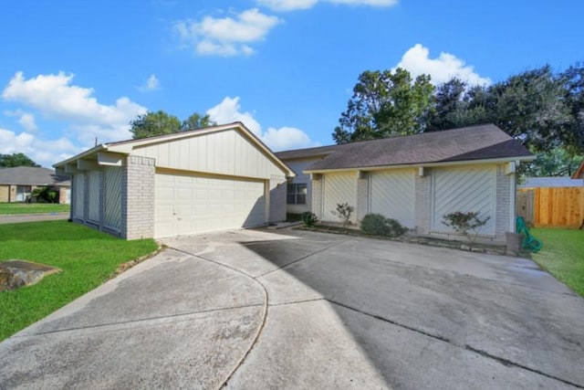 view of front of home featuring brick siding, a detached garage, a front yard, and fence