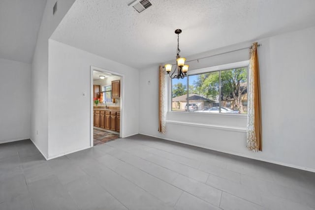 unfurnished dining area with a chandelier and a textured ceiling