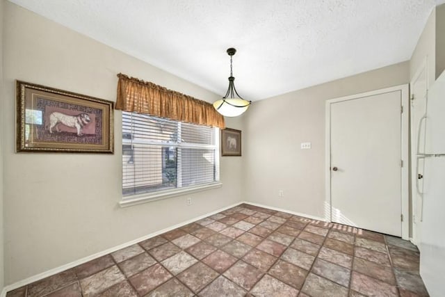 unfurnished dining area featuring a textured ceiling