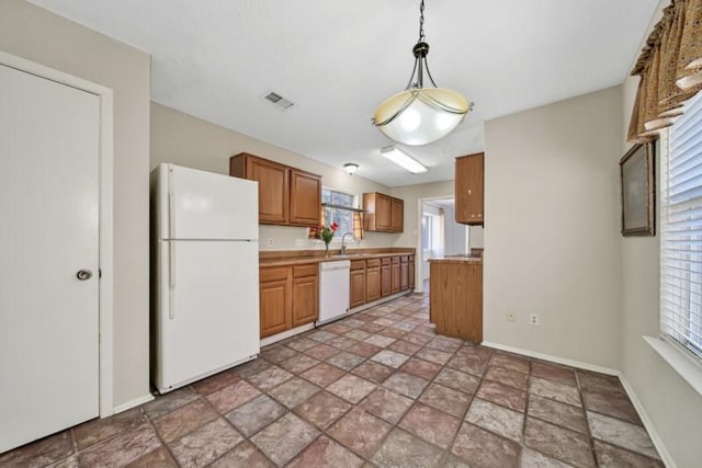 kitchen with white appliances, plenty of natural light, hanging light fixtures, and sink