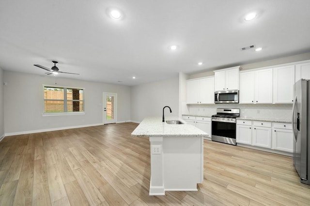 kitchen with a center island with sink, white cabinets, sink, and appliances with stainless steel finishes