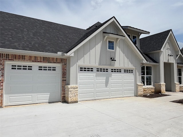 2419 Ryan St, Brenham, TX 77833 - view of front of property with board and batten siding, a shingled roof, an attached garage, stone siding, and concrete driveway
