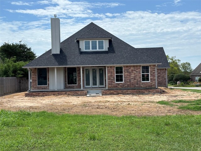 2419 Ryan St, Brenham, TX 77833 - back of property featuring a chimney, brick siding, a shingled roof, and a porch