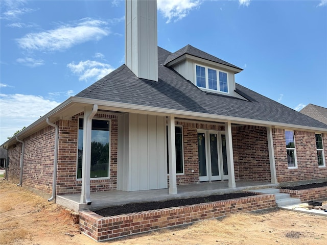 2419 Ryan St, Brenham, TX 77833 - rear view of house featuring a chimney, a porch, brick siding, and a shingled roof