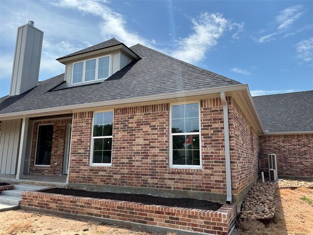 2419 Ryan St, Brenham, TX 77833 - view of home's exterior featuring brick siding, a chimney, and roof with shingles