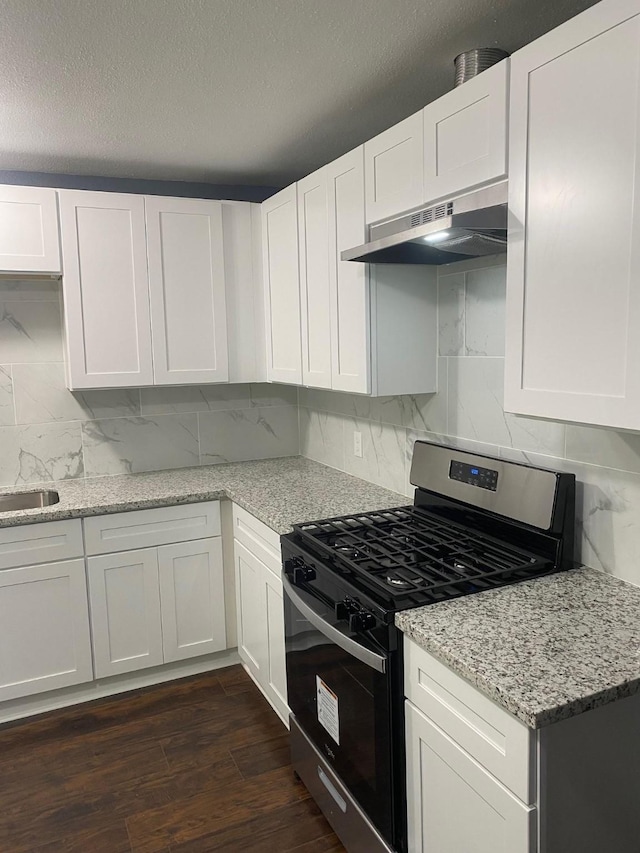 kitchen with dark hardwood / wood-style flooring, light stone counters, stainless steel gas range oven, ventilation hood, and white cabinets