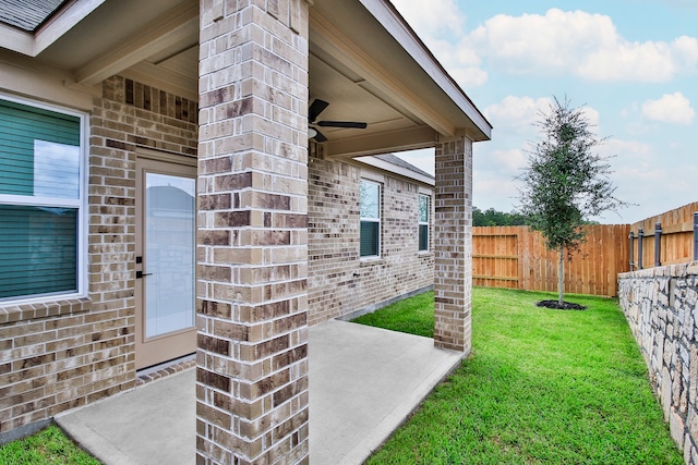 view of exterior entry featuring ceiling fan and a yard