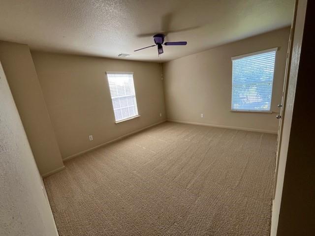 unfurnished room with a textured ceiling, ceiling fan, and light carpet