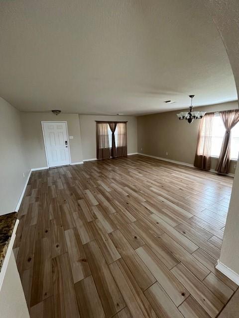 unfurnished living room with a chandelier and light hardwood / wood-style floors