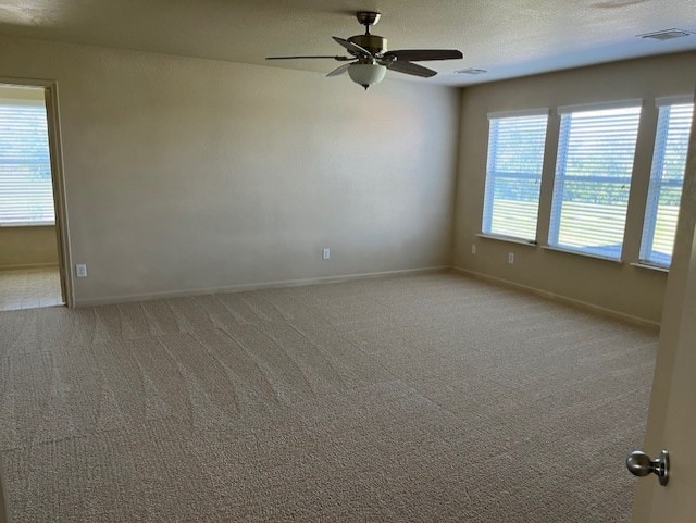 spare room featuring a textured ceiling, light colored carpet, and ceiling fan