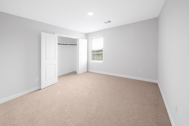 unfurnished bedroom with light carpet and a closet