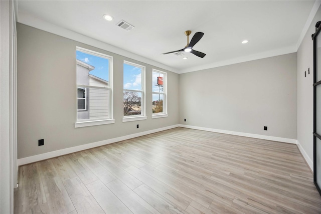 empty room with a barn door, crown molding, ceiling fan, and light wood-type flooring