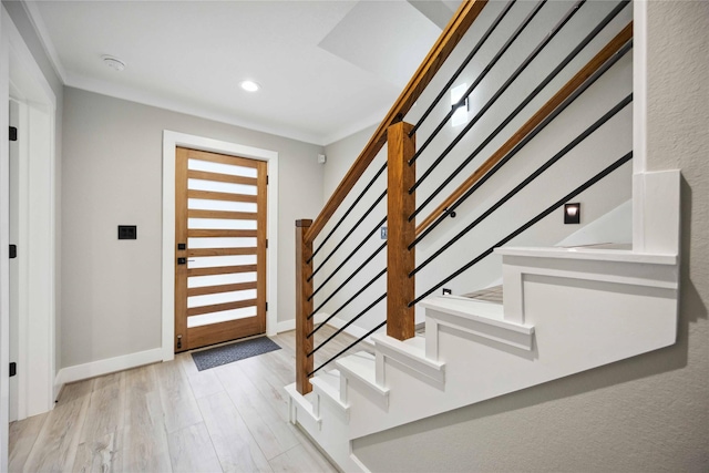 foyer entrance with crown molding and light hardwood / wood-style floors