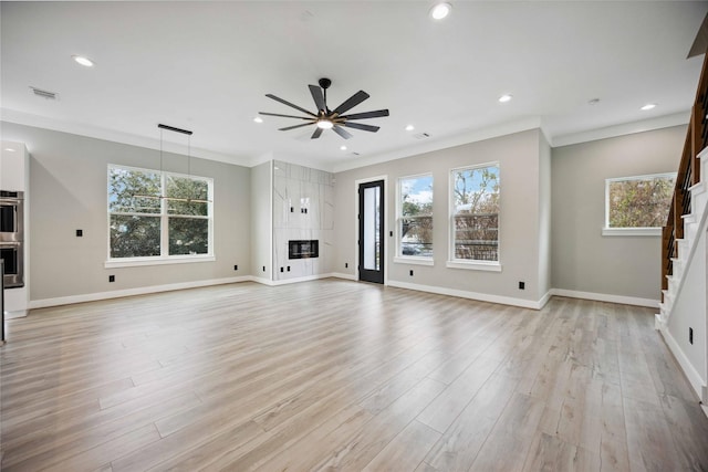 unfurnished living room with ceiling fan, ornamental molding, and light wood-type flooring