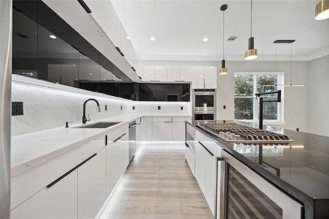 kitchen featuring white cabinets, stainless steel appliances, hanging light fixtures, and sink