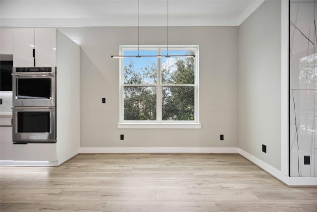 unfurnished dining area with ornamental molding, light hardwood / wood-style floors, and an inviting chandelier