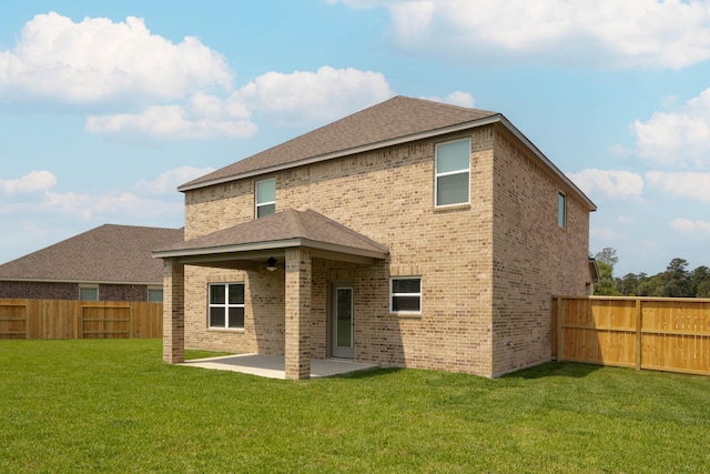 rear view of property featuring ceiling fan, a yard, and a patio