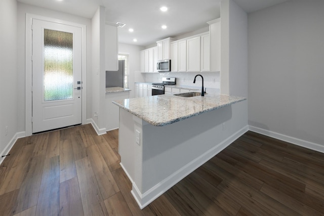 kitchen with white cabinetry, sink, light stone counters, kitchen peninsula, and appliances with stainless steel finishes