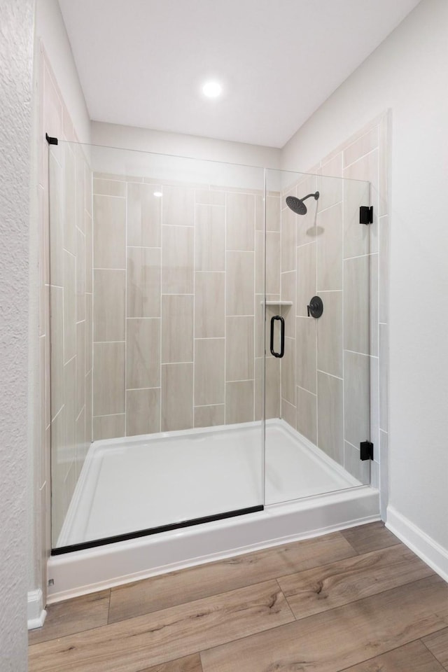 bathroom featuring hardwood / wood-style flooring and walk in shower