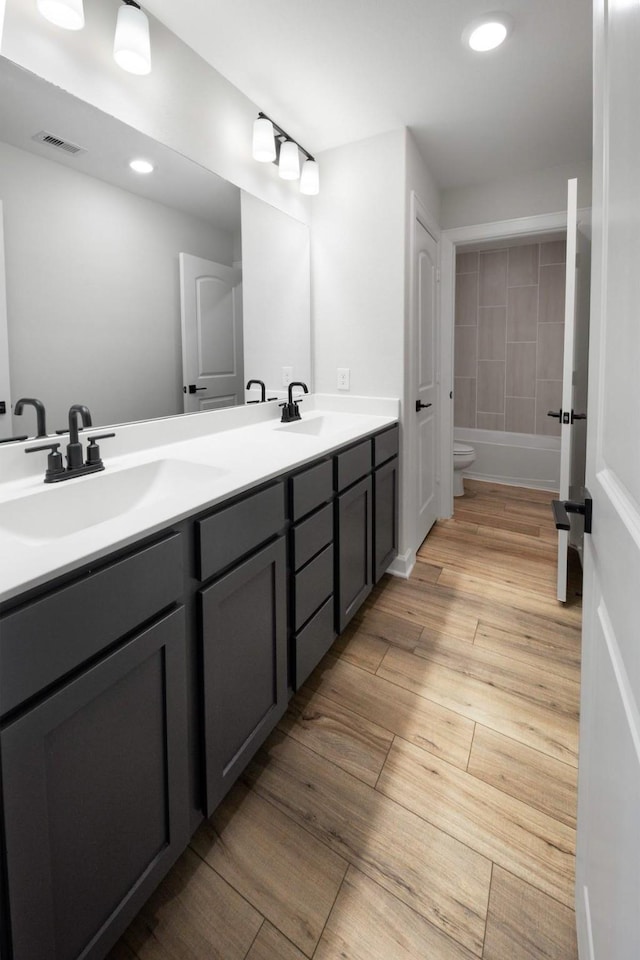 bathroom with vanity, a bath, and toilet