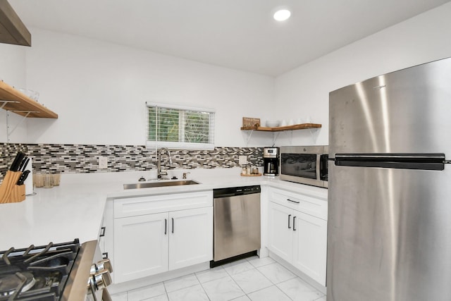 kitchen with appliances with stainless steel finishes, light tile patterned floors, white cabinetry, and sink