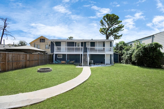 back of property with a fire pit, a deck, and a yard